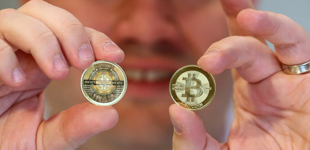 A person holding 2 physical BTC coins