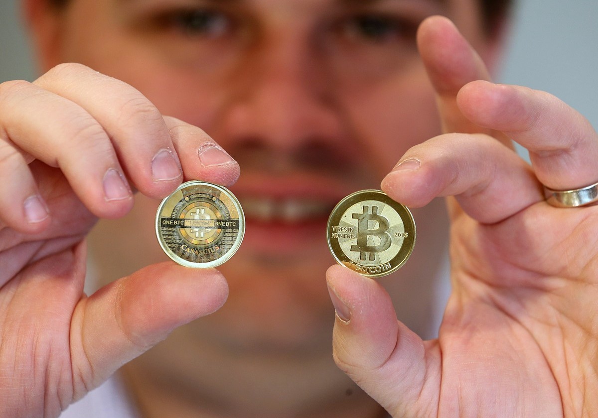 A person holding 2 physical BTC coins