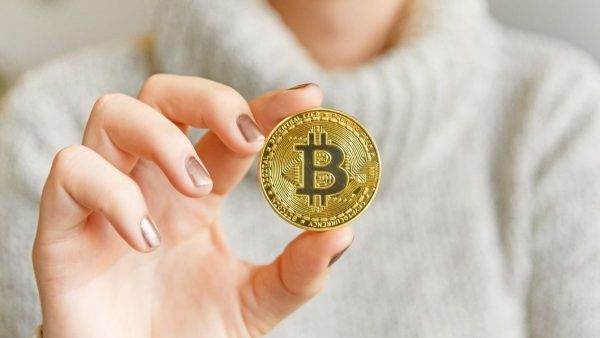 A person holding a Bitcoin coin